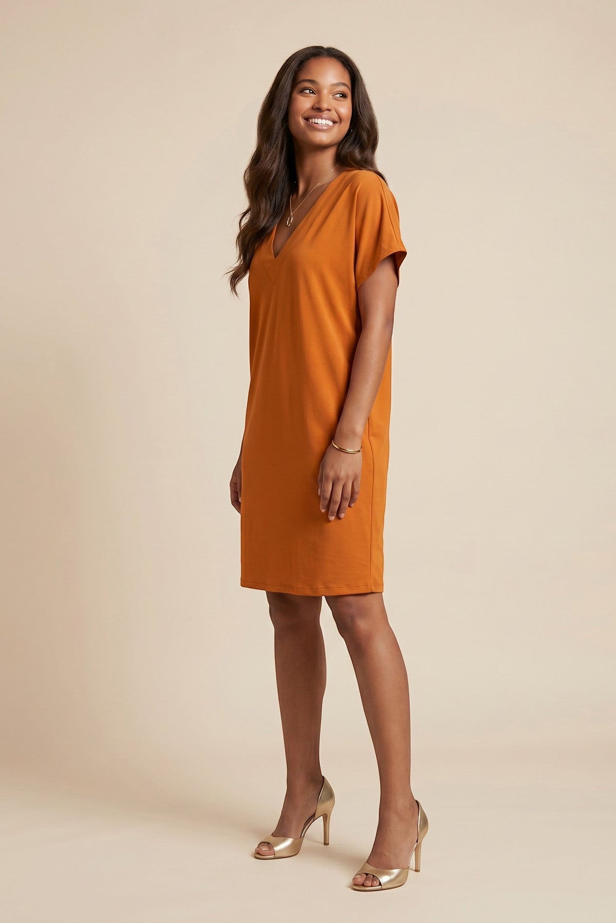 Osanna Creazione orange short straight V-neck dress with short sleeves and a matching belt, worn by a model with gold heels.