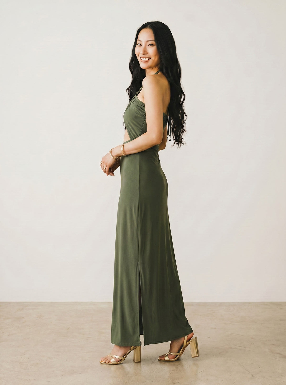 Osanna Creazione Robe longue verte kaki dos nu avec découpe ventre, fente latérale et bijou doré. Matière fluide.