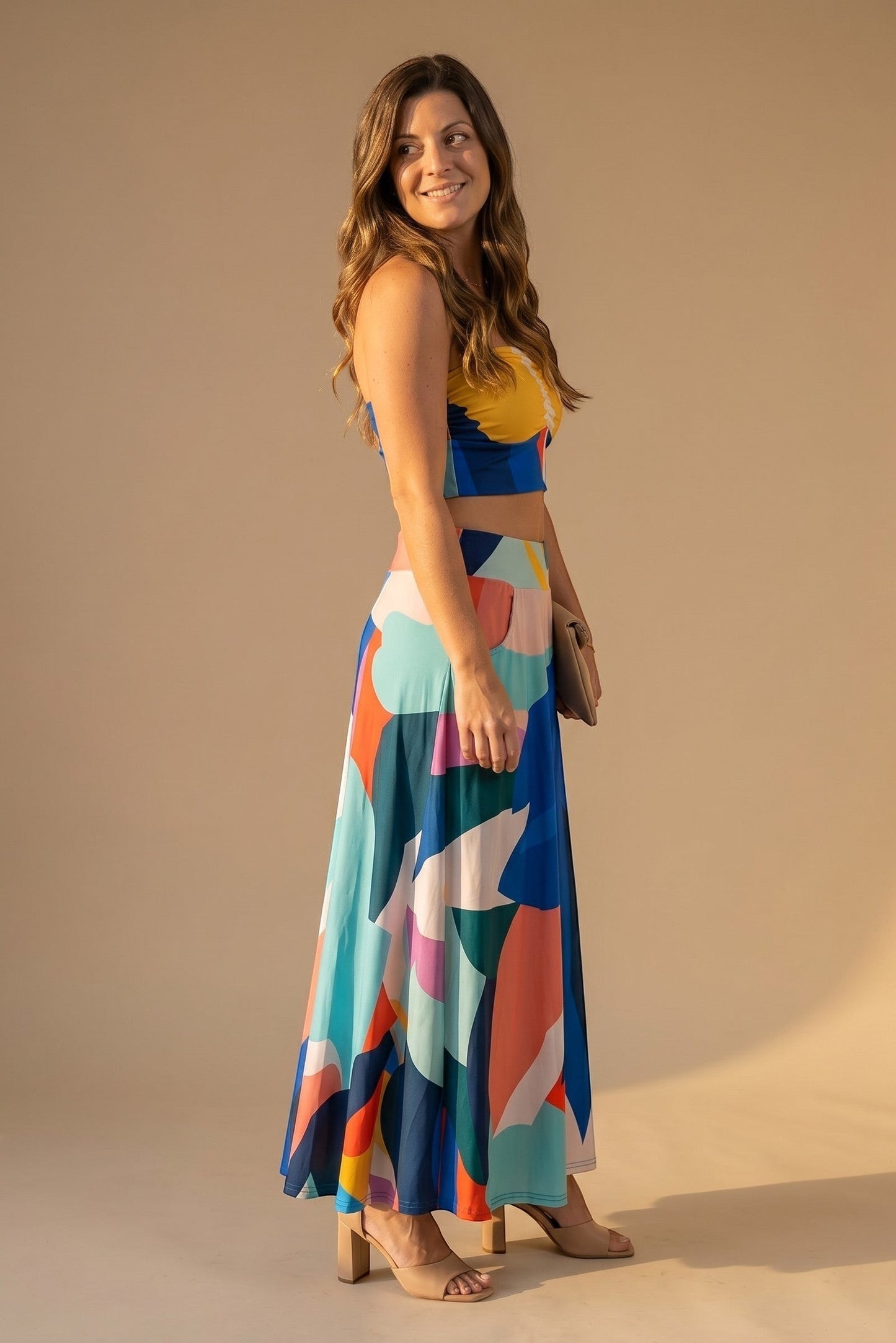 Osanna Creazione women's long, flowing skirt with a vibrant abstract print in blue, yellow, pink, and teal. Features pockets and an A-line cut.
