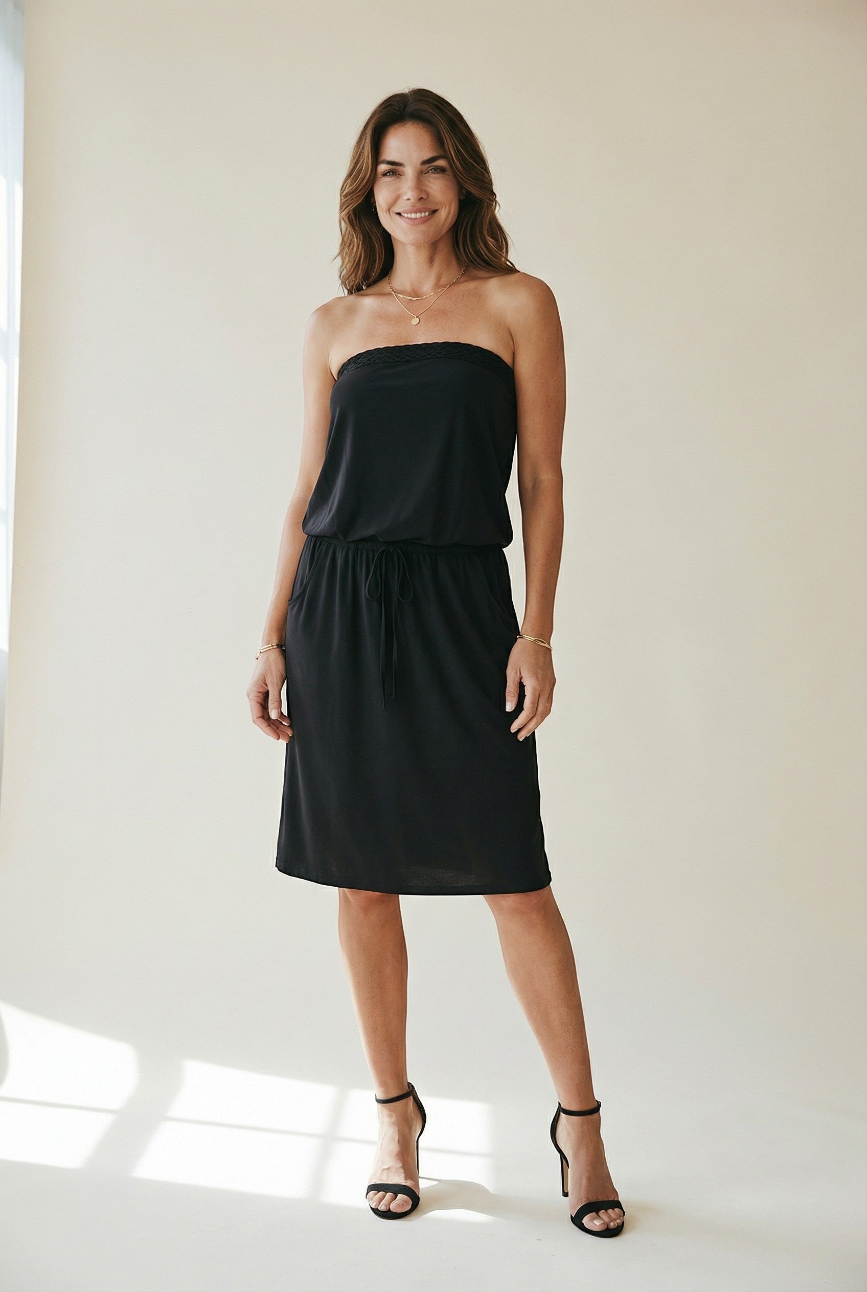 Osanna Creazione black strapless midi dress with cinched waist and pockets, featuring a blousant top and flared skirt.