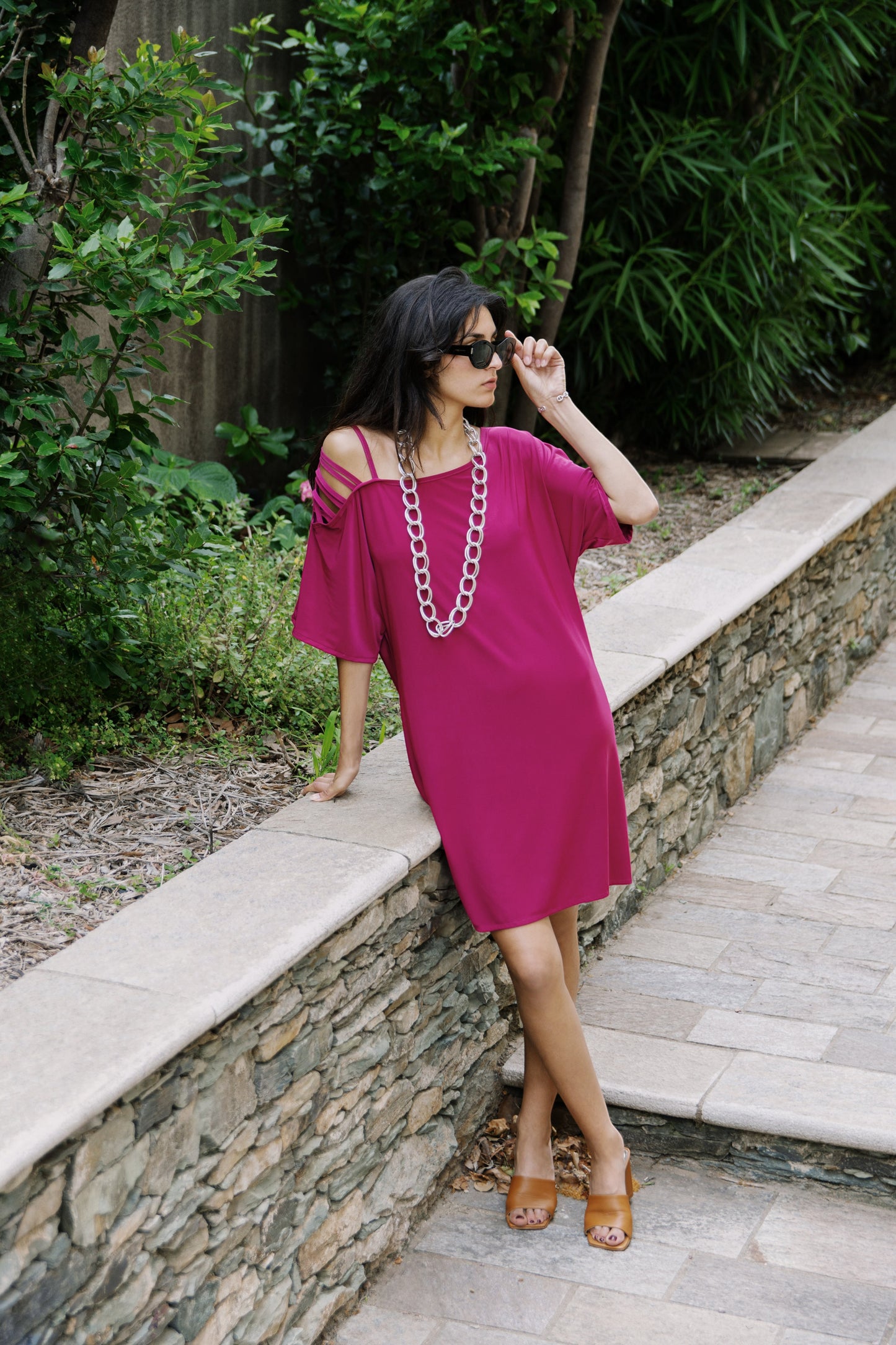Osanna Creazione Alzira short magenta dress with mid-sleeves and a single cold shoulder detail, sold with a belt.