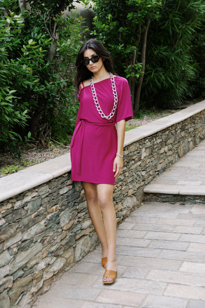 Osanna Creazione Alzira magenta short dress with mid-sleeves, belted waist, and one-shoulder detail.