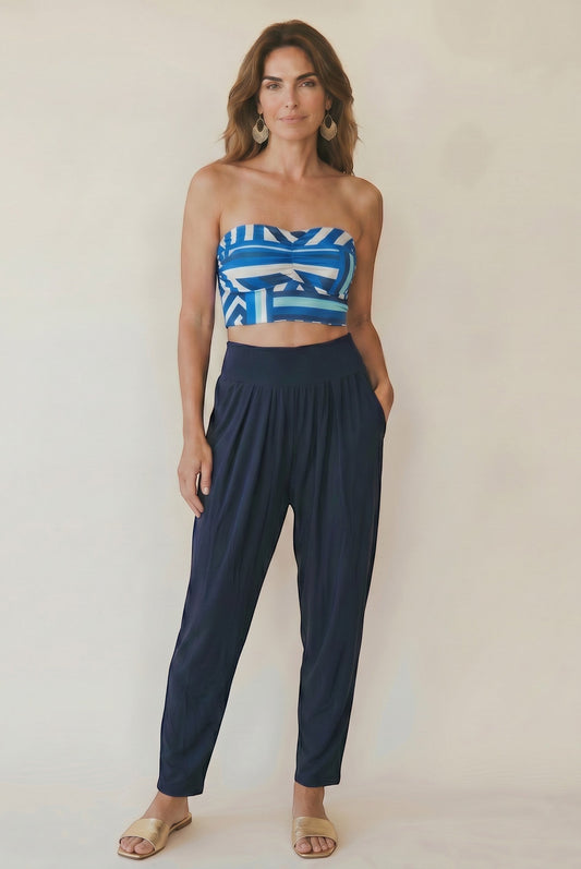 Osanna Creazione navy blue fluid tapered pants with high elasticated waist and side pockets, worn by a model with a patterned bandeau top.