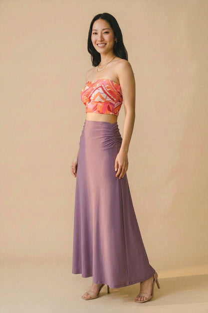Osanna Creazione Florence long purple ruched waist maxi skirt, fluid and comfortable, worn by a model with a patterned bandeau top.