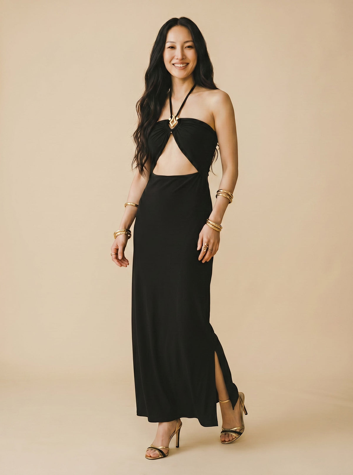 Robe longue noire dos nu Osanna Creazione avec découpe ventre, bijou doré et fente latérale. Modèle fluide.