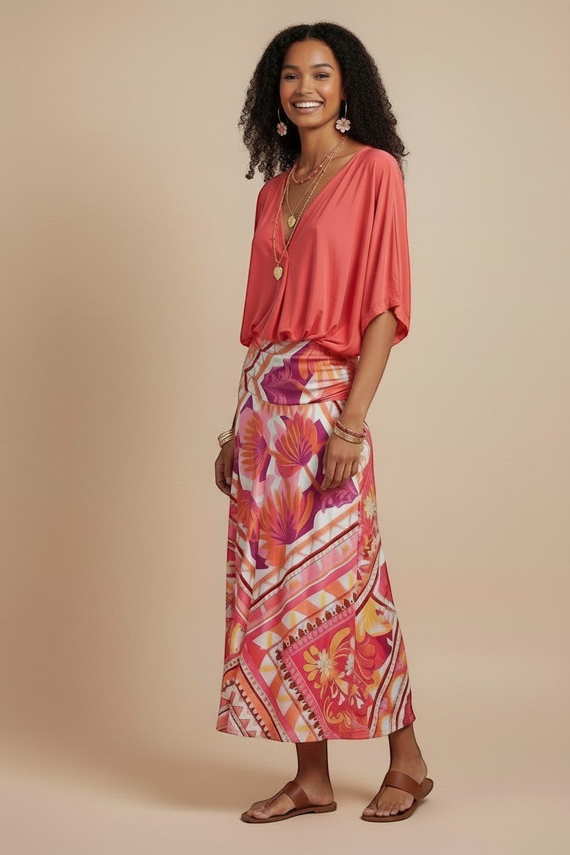 Osanna Creazione : top fluide corail à col V et manches larges, coupe ample, porté par une femme avec une jupe longue imprimée.